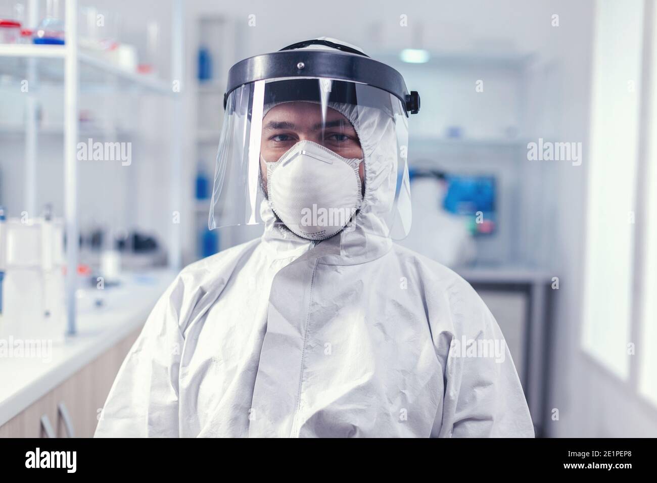 Científico de bioquímica usando máscara y protector facial como precaución  de seguridad para el brote de covid19 trabajando en laboratorio.  Investigador sobretrabajado vestido con traje protector contra la invección  con coronavirus durante
