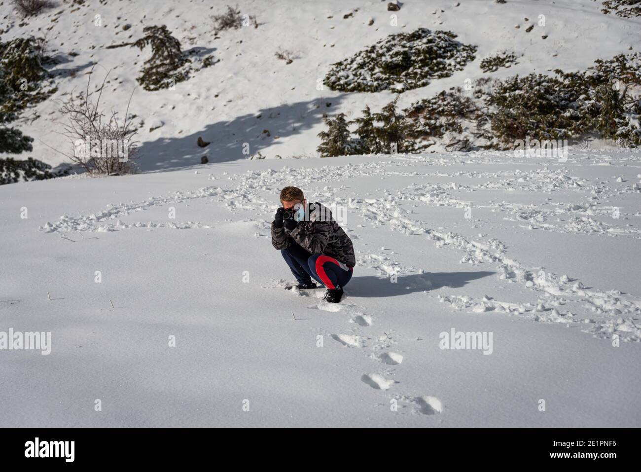 hombre joven haciendo fotos en un paisaje cubierto de nieve, pasatiempo o actividad de ocio. Foto de stock