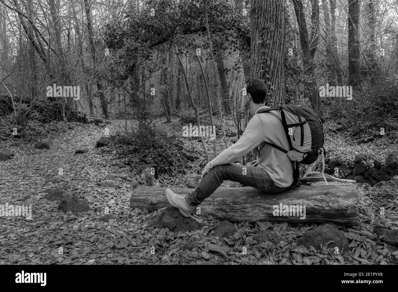 Hombre sentado con mochila en los bosques mirando horizonte en el bosque.con estilo Estilo de vida al aire libre del excursionista.concepto del wanderlust del recorrido.Fotografía del blanco y negro wit Foto de stock