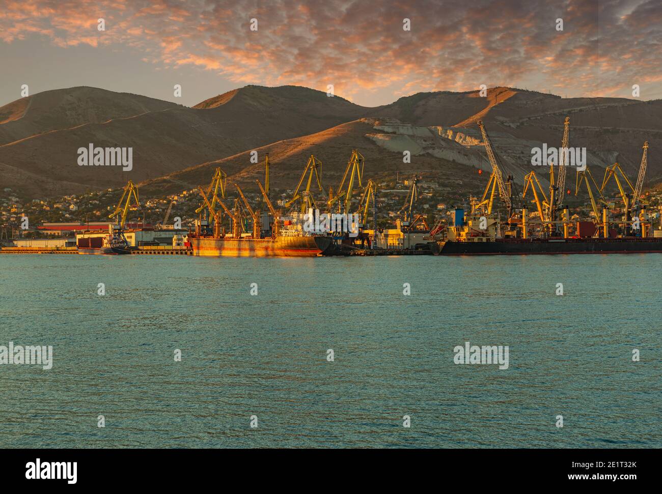 Vista de las instalaciones portuarias y mecanismos del Novorossiysk Puerto marítimo comercial por la noche antes de la puesta de sol Foto de stock