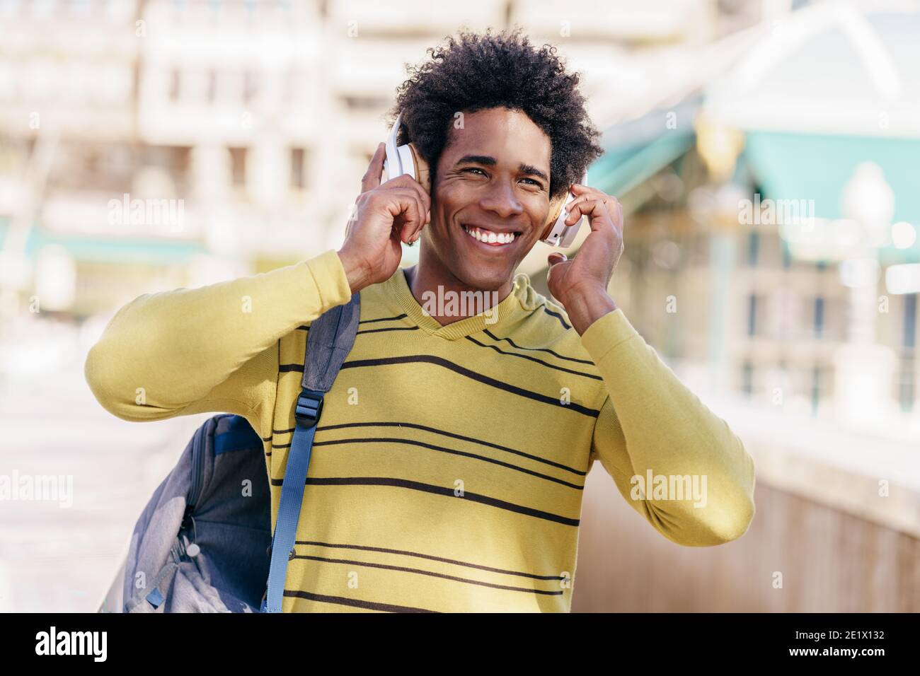 Hombre negro escuchando música con los auriculares inalámbricos de visita turística en Granada Foto de stock