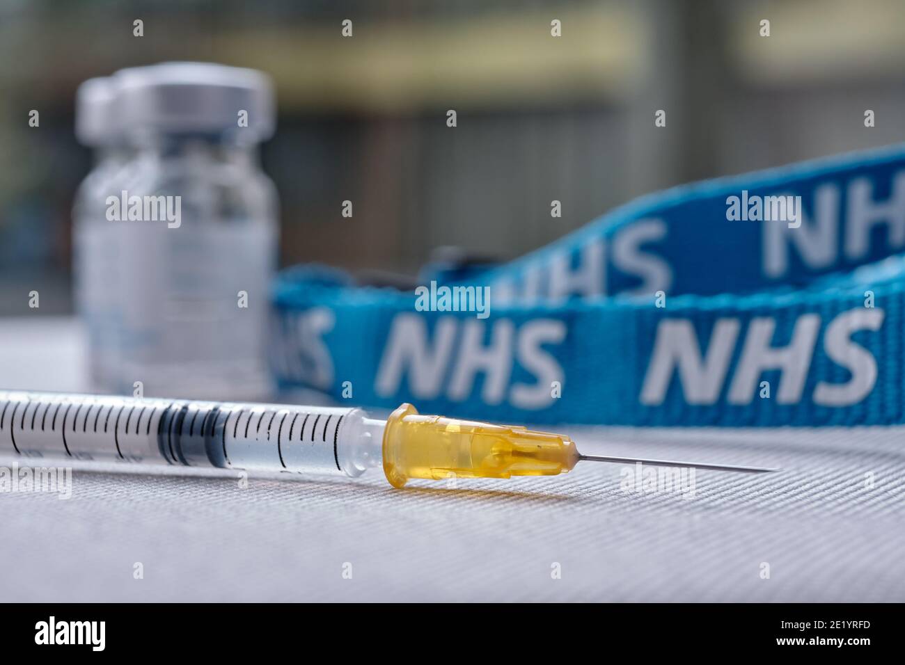 Stafford, Reino Unido - Enero 10 2021: Concepto de vacuna NHS. Jeringa, viales de inyección y cordón NHS. Enfoque selectivo. Foto de stock