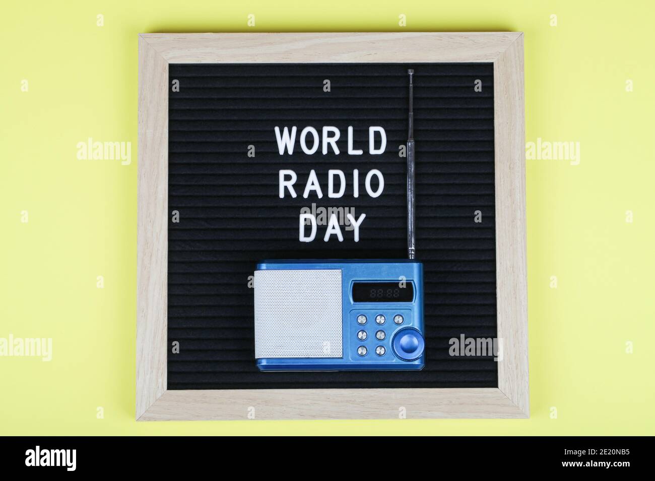 pizarra de letras negra con texto día mundial de la radio con la radio azul sobre fondo amarillo. Vista superior. plano de fondo mínimo. Foto de stock