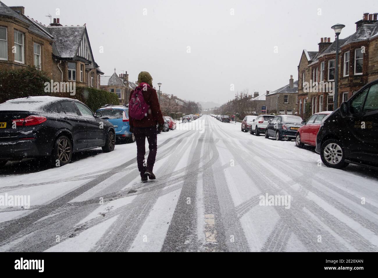 Una mujer caminando a lo largo de un camino cubierto de nieve en Edimburgo, Escocia, Reino Unido. Foto de stock