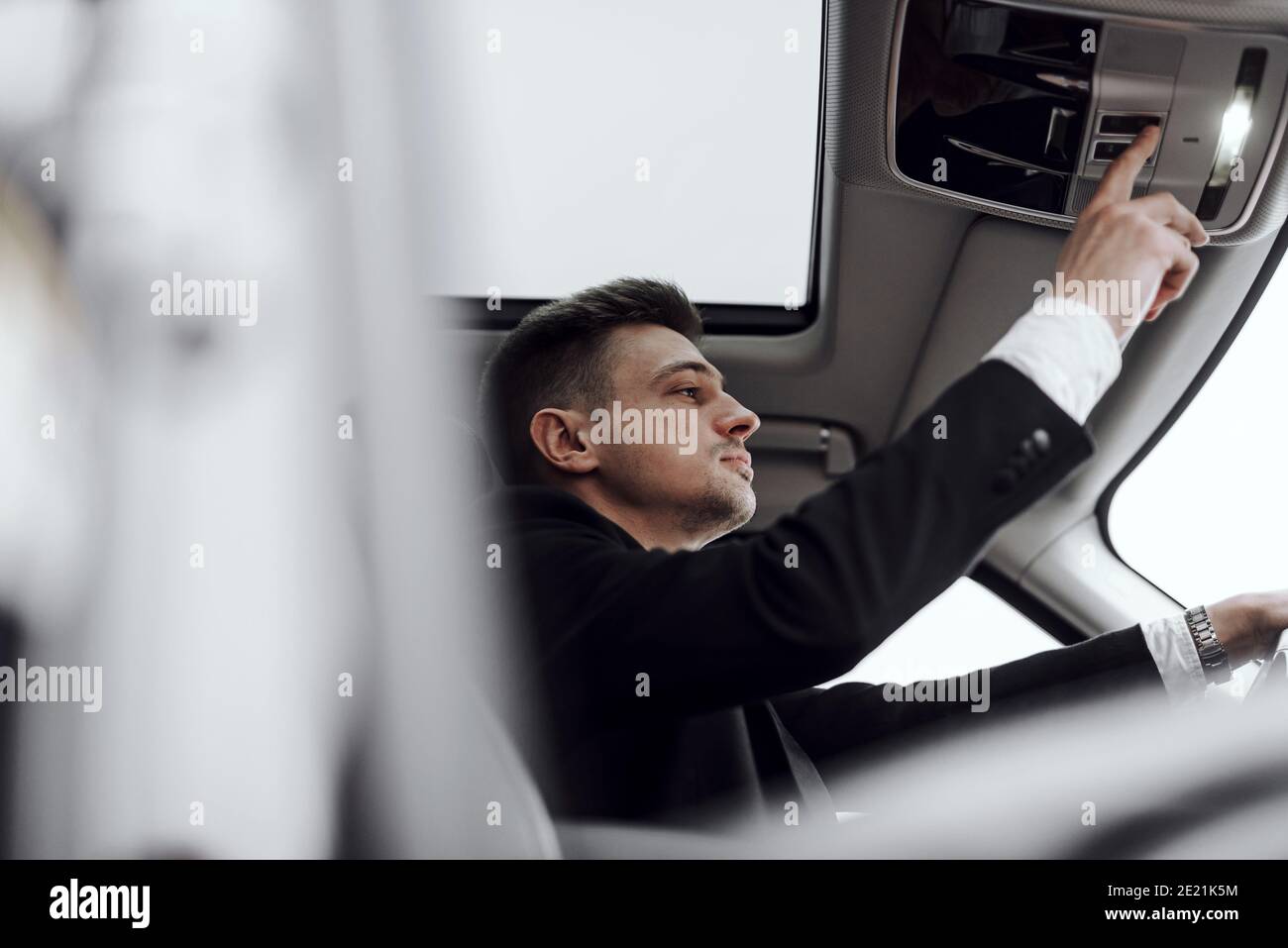 Foto recortada de hombre guapo que alquila un automóvil moderno mientras pulsa el botón. Concepto de alquiler y cambio Foto de stock