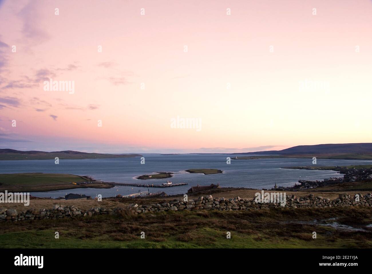 Vista desde la cima de la colina de dos pequeñas islas y.. puerto en las islas Orkney con cielo despejado Foto de stock
