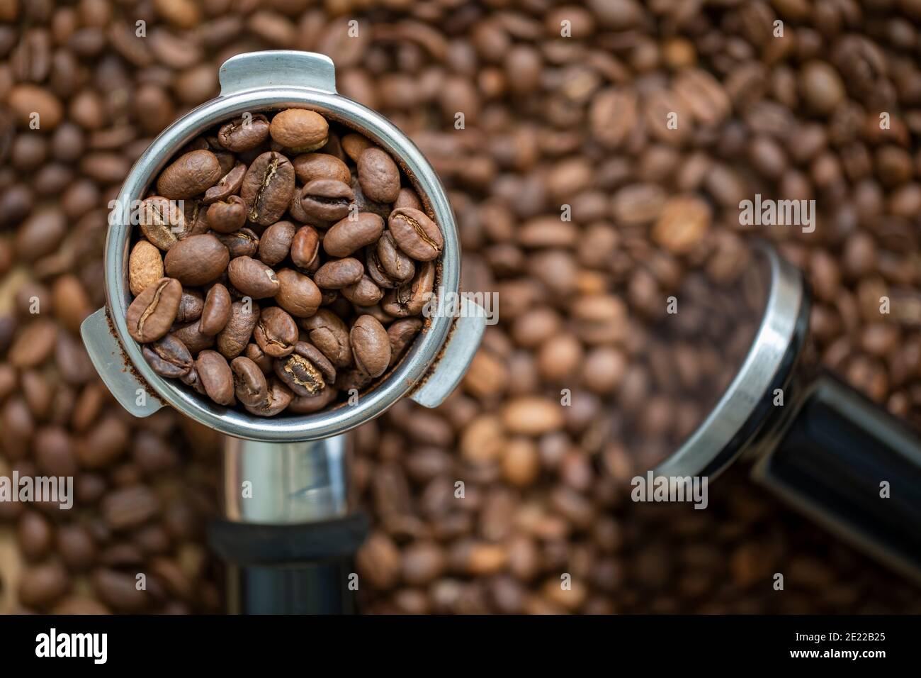 Granos de café en un portafiltro, listos para ser hechos en una dosis caliente de espresso Foto de stock