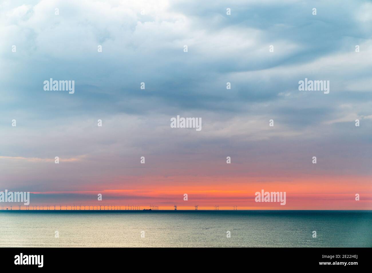 El parque eólico marino Thanet en el horizonte de la costa de Kent. Amanecer, cielo del amanecer, banda de cielo rojo en el horizonte bajo con nubes grises pesadas por encima. Foto de stock