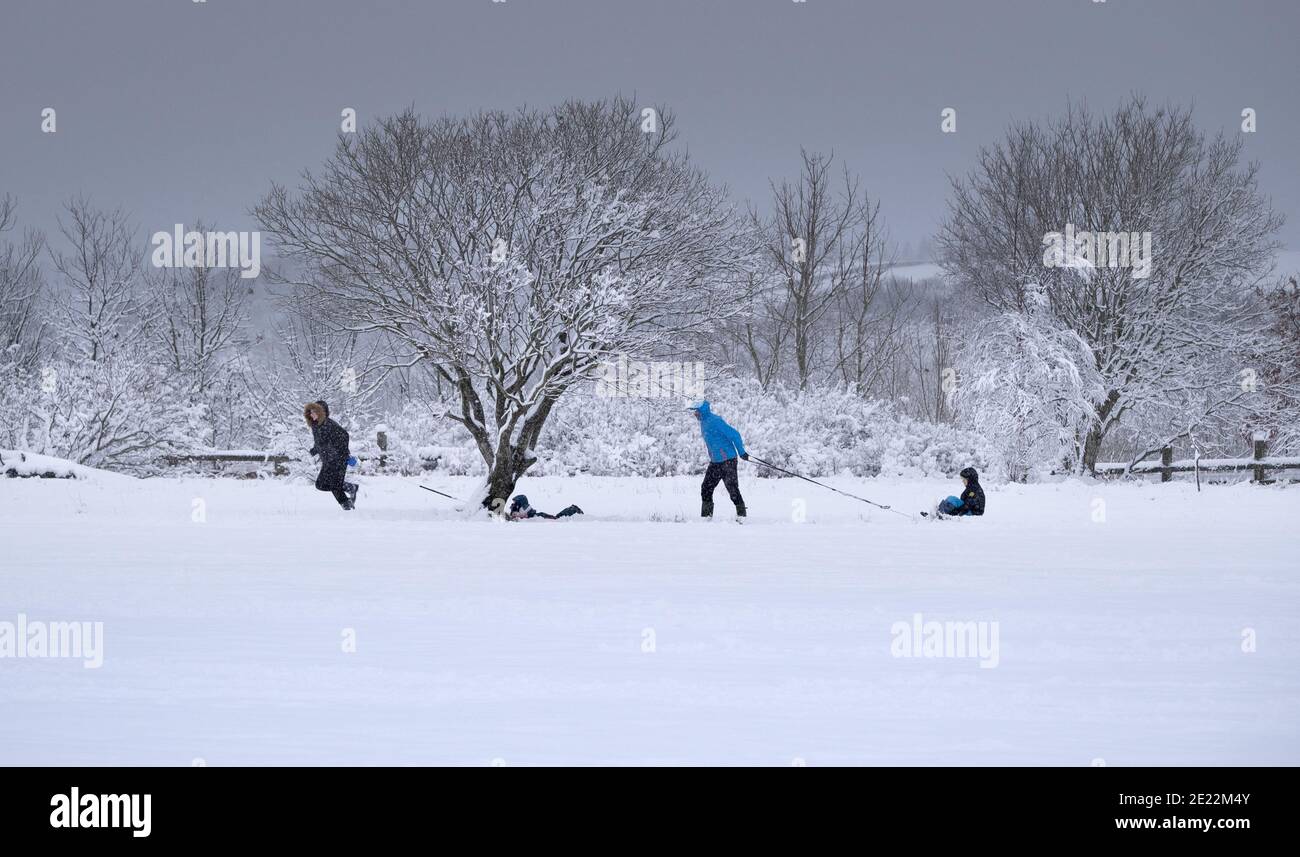 Diversión al aire libre en invierno, actividades y ejercicio. Familias con niños en trineo en nieve profunda. Foto de stock