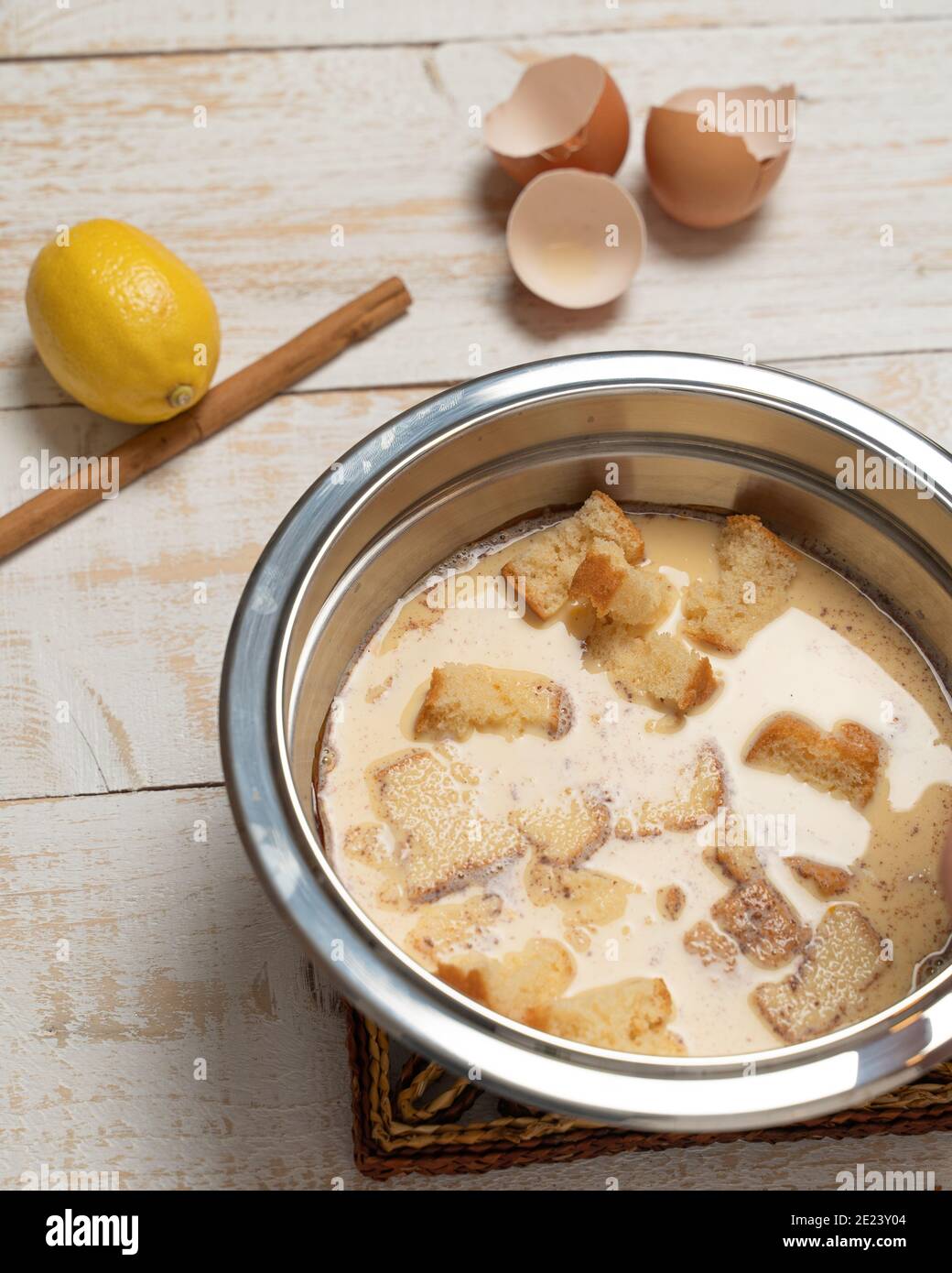 Tiro vertical de un tazón de leche con pan, cáscaras de huevo agrietadas,  limón y canela en una mesa de tablas Fotografía de stock - Alamy