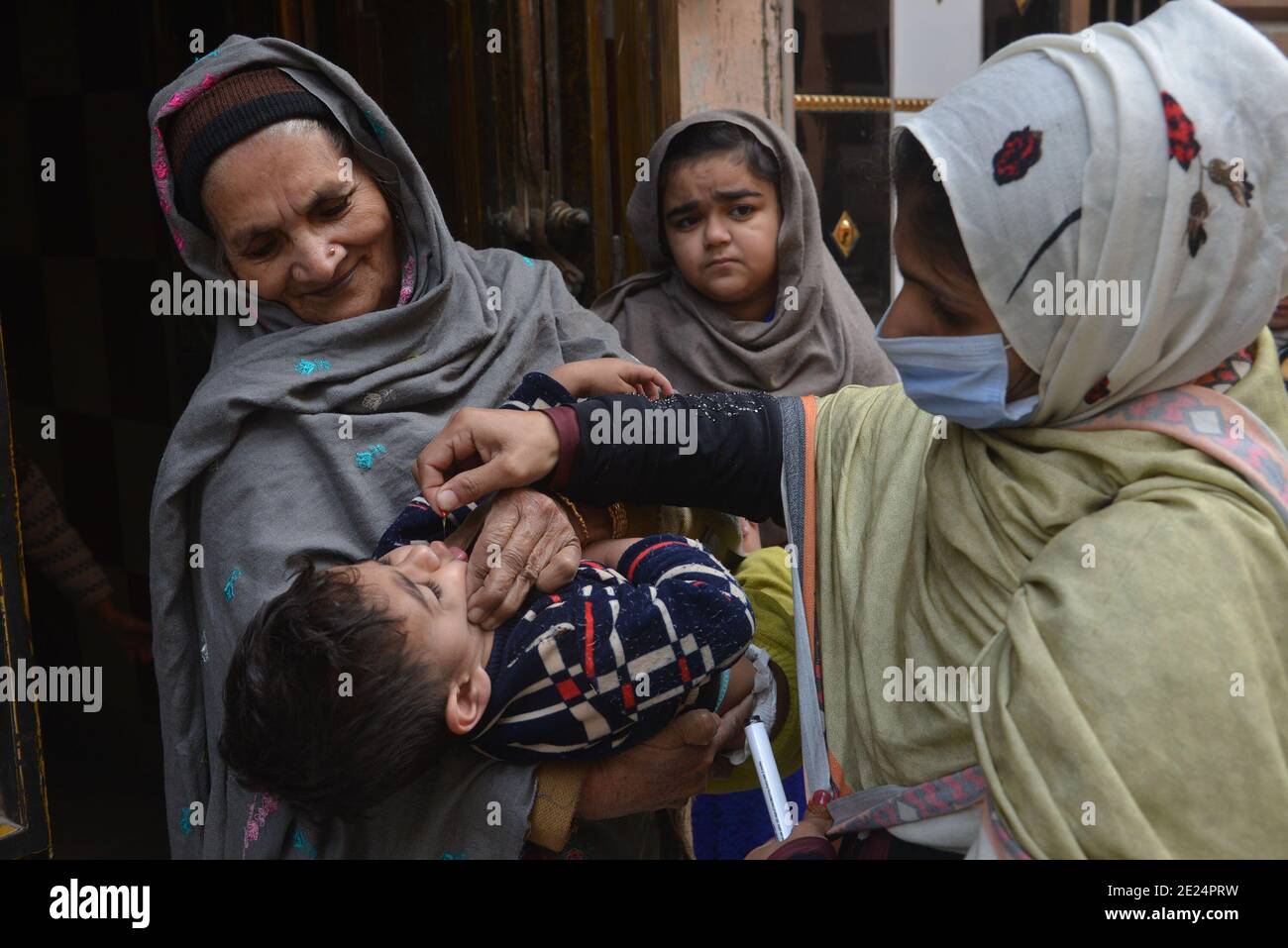 Un trabajador sanitario paquistaní administra una vacuna contra la polio a un niño Durante una campaña puerta a puerta de vacunación contra la polio en Lahore Foto de stock
