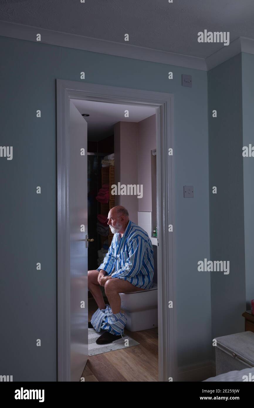 Hombre mayor en su cuarto de baño en-suite temprano una mañana. Foto de stock