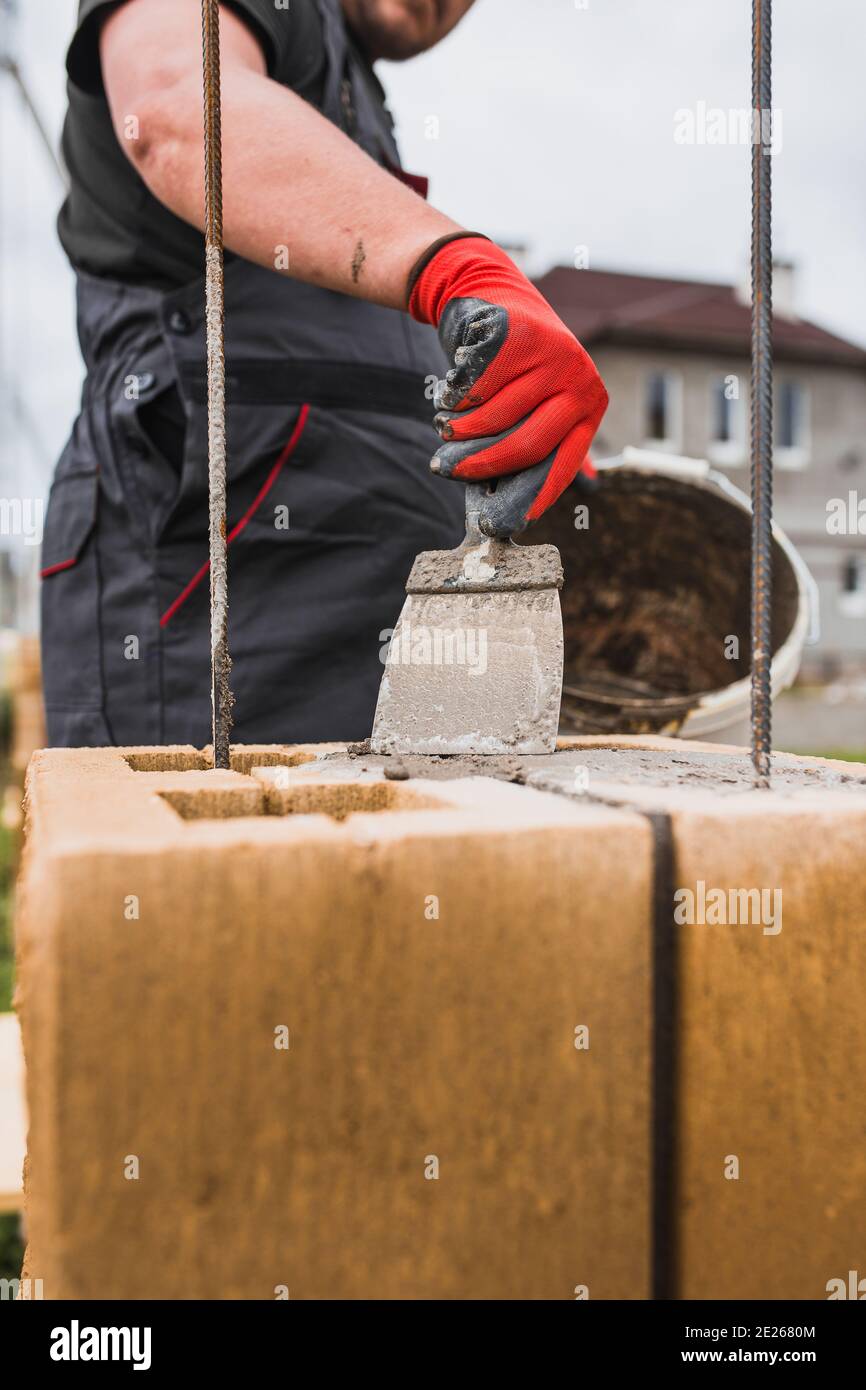Adhesivo a base de cemento para bloques de piedra de albañilería y ladrillo en construcción - un profesional de la bricklayer en el trabajo Foto de stock