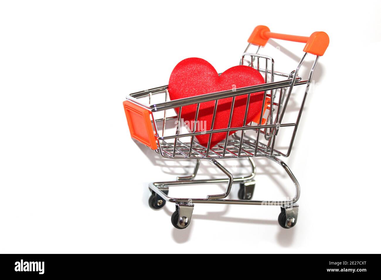 Corazón rojo en carrito de compras sobre fondo blanco Foto de stock