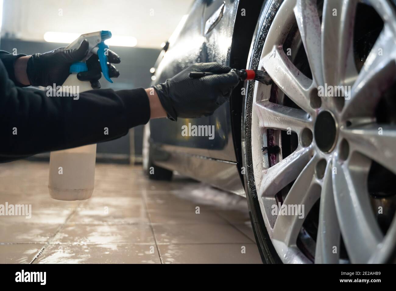 Proceso de limpieza de las ruedas del coche. El limpiador de llantas  produce una reacción química púrpura al eliminar las inclusiones de metal o  hierro y el polvo de los frenos. Detalle