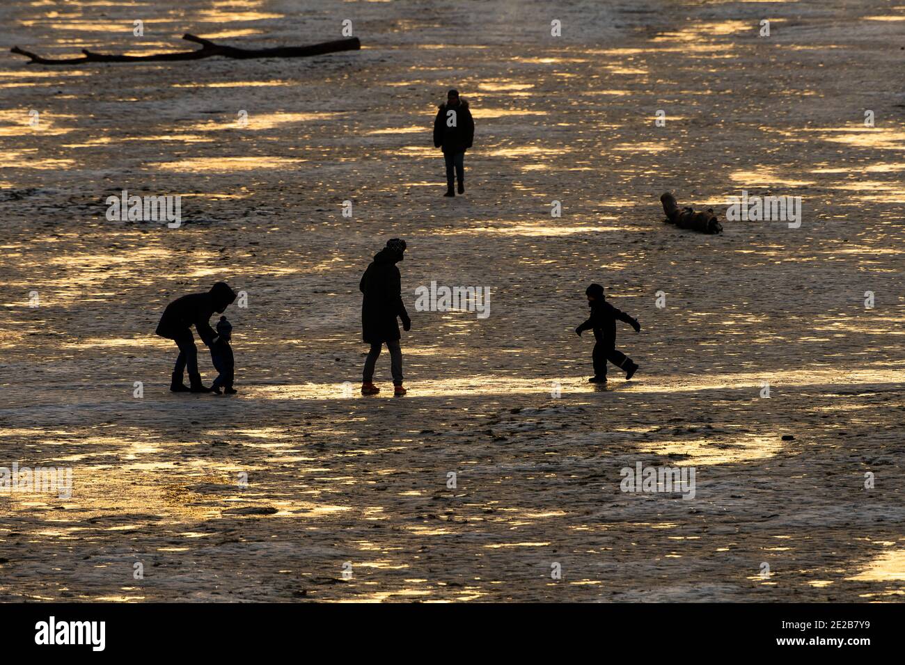Munich, Alemania. 13 de enero de 2021. Una familia con niños se deslizó a través de las orillas congeladas del Isar, brillando en la última luz del día. Crédito: Peter Kneffel/dpa/Alamy Live News Foto de stock