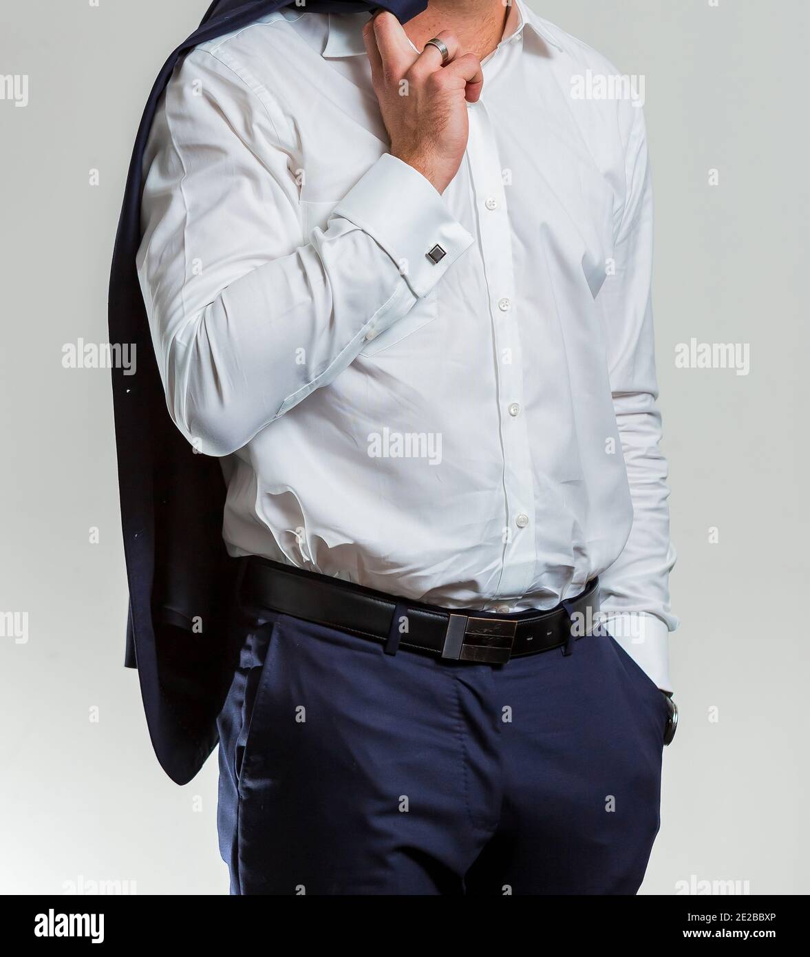Disparo vertical de un hombre vestido con una camisa blanca con pantalón azul oscuro, sosteniendo un traje Fotografía de -
