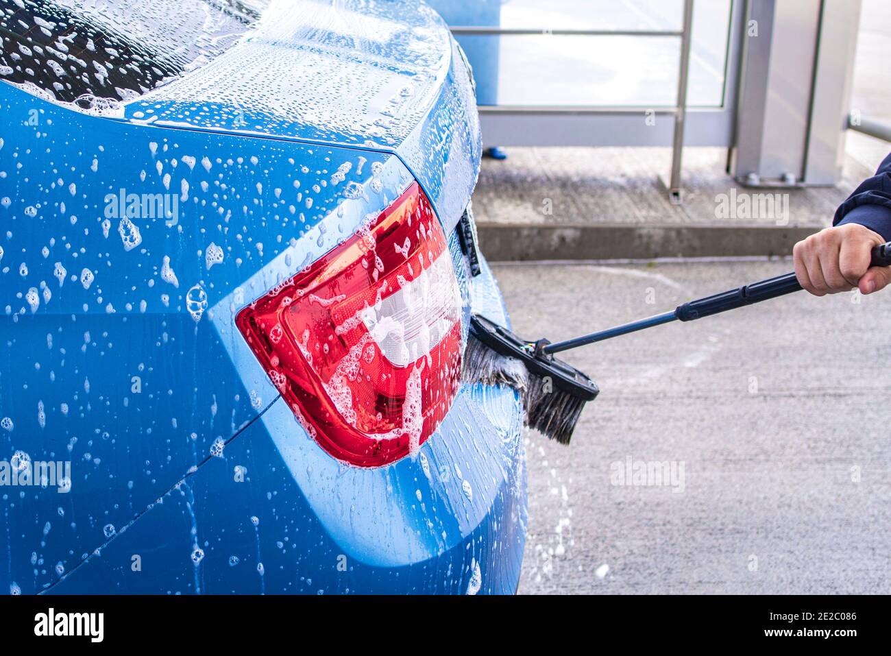 Un hombre lava un coche por su cuenta. Auto-servicio de lavado de Lavado de coches barato.Man lavar su coche en una estación de auto-servicio de lavado de coches Fotografía de stock -