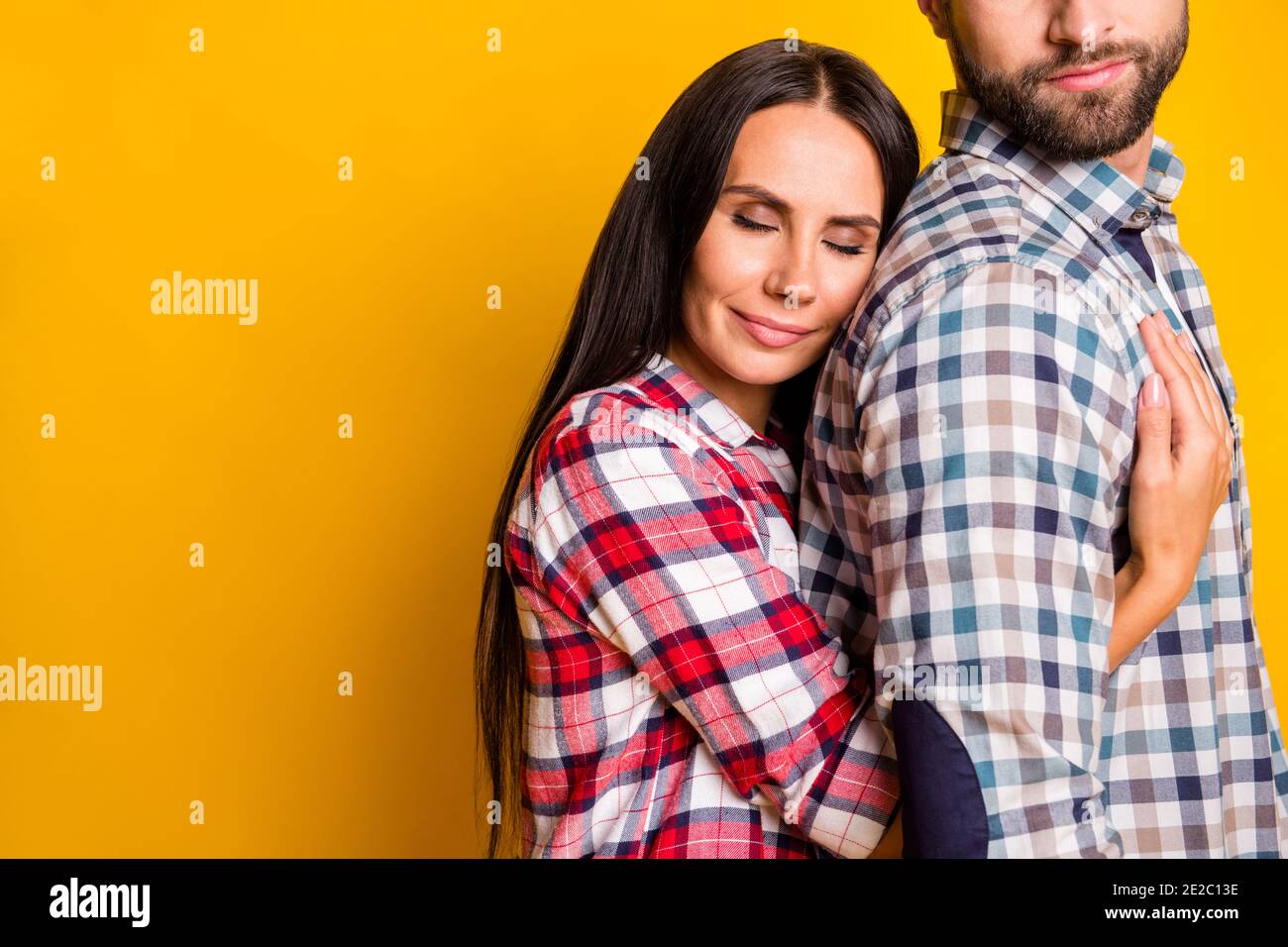 Foto retrato de mujer abrazando al hombre desde atrás aislado fondo de color amarillo intenso con espacio en blanco Foto de stock