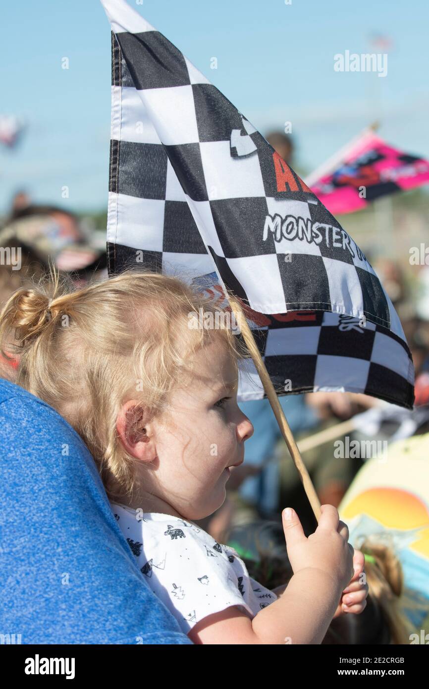 Un joven fan de las carreras mantiene una bandera a cuadros durante las carreras de camiones monstruo en Nápoles, Florida Foto de stock