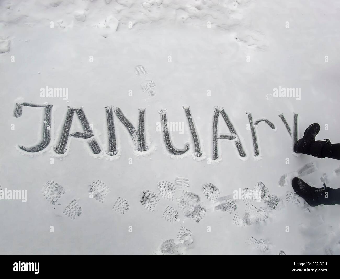 la palabra enero niña escribió en la nieve con ella arranque Foto de stock