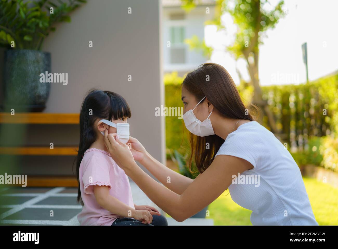 La madre asiática ayuda a su hija a usar máscara de protección para proteger la situación del brote de coronavirus Covid-19 antes de ir a la escuela. Prepárate para la escuela Foto de stock