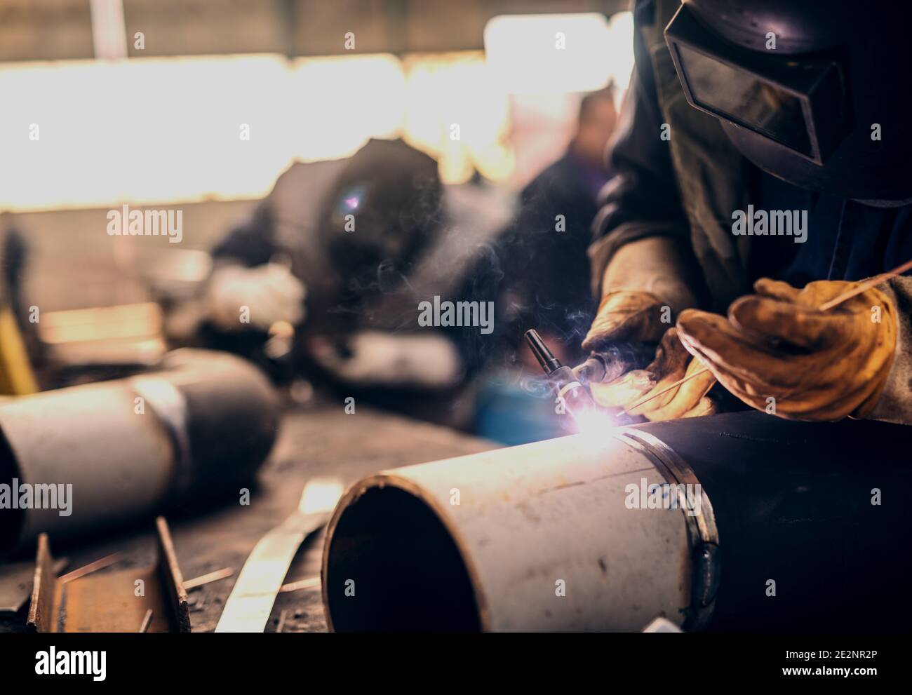 Soldadores profesionales en uniforme de protección y máscara de soldadura  de tubería de metal en el taller Fotografía de stock - Alamy