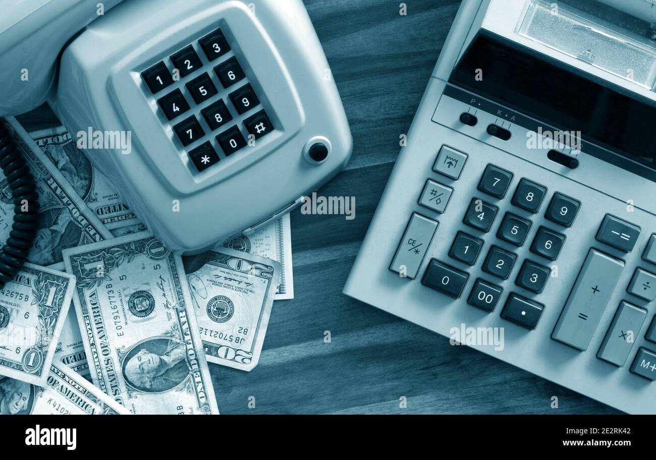 Calculadora antigua, teléfono y dólares en el escritorio Foto de stock