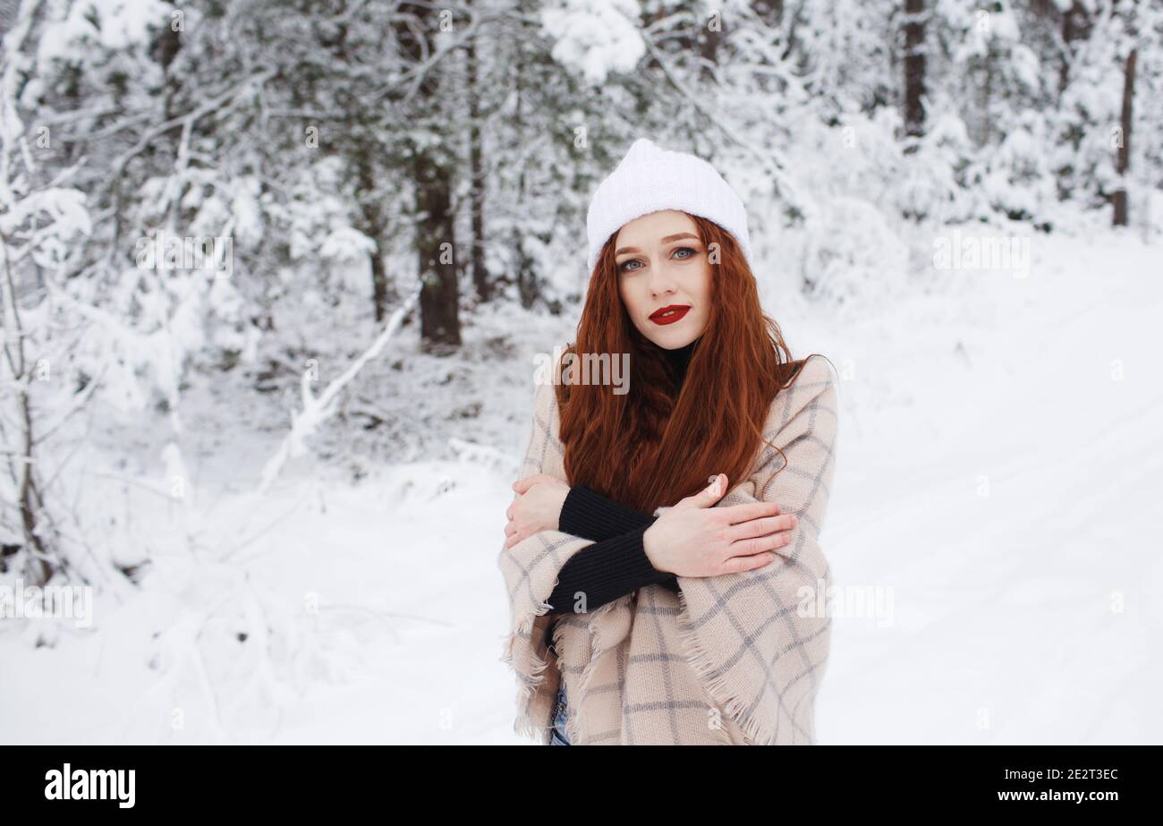 Una niña con el pelo rojo brillante largo en un fondo de invierno.una mujer  de pelo rojo en una gorra blanca Fotografía de stock - Alamy