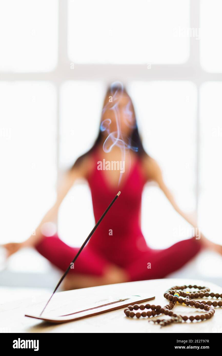 Palillo de sándalo aromático y rosario en la mesa contra el fondo de un  instructor de yoga meditante en el desenfoque Fotografía de stock - Alamy