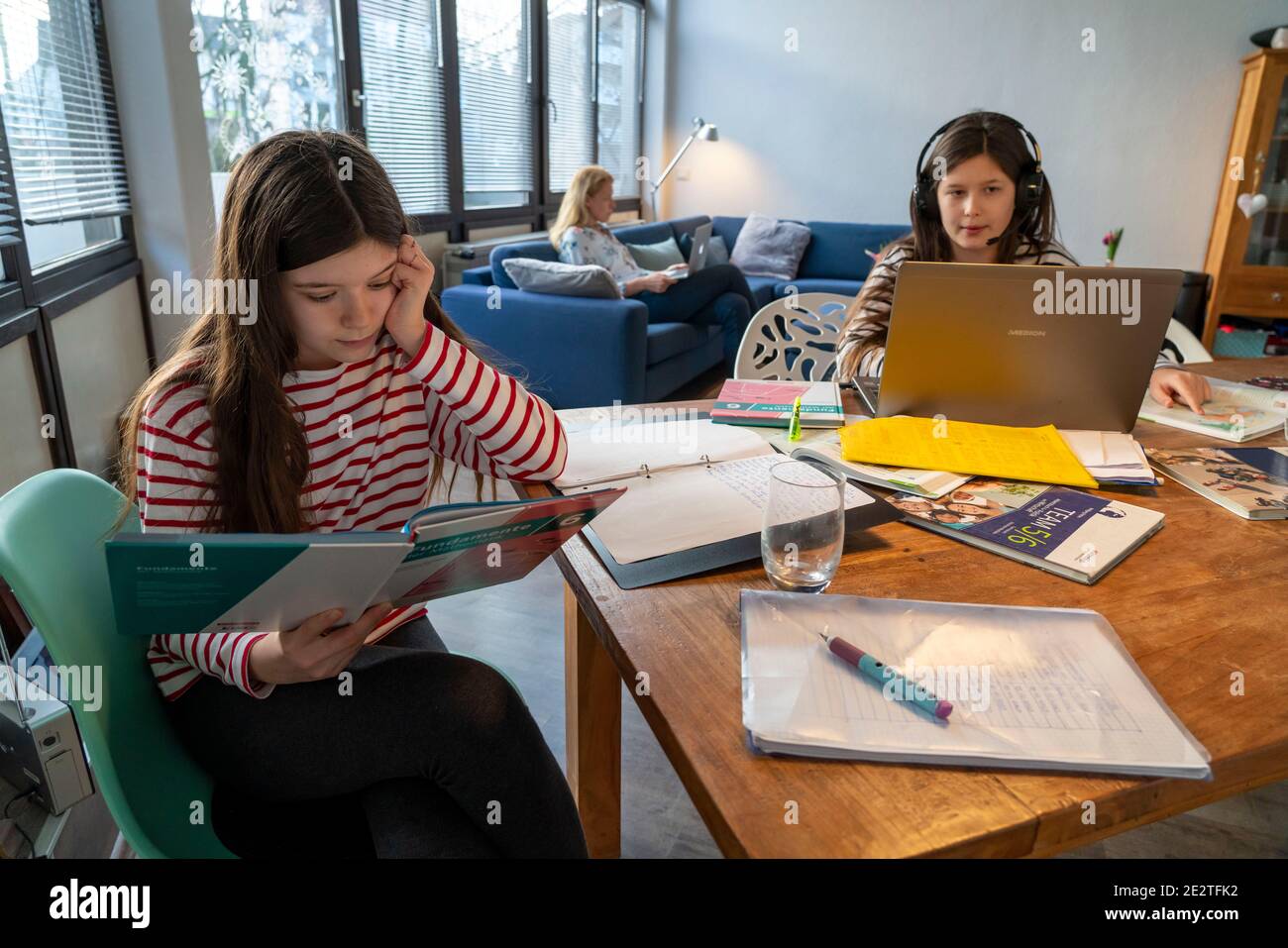 Durante el cierre de enero de 2021, los niños que estudian en casa para ir a la escuela, su madre en la oficina doméstica trabajando en el ordenador portátil con vidade Foto de stock