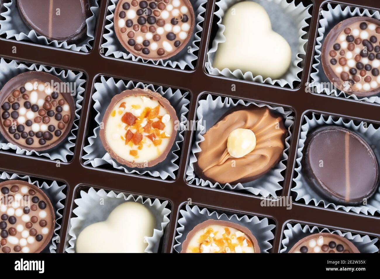 Diferentes pralinas de chocolate. Caja de pralinés belgas de diferentes formas. Surtido de bombones blancos, oscuros y de leche de bélgica Foto de stock