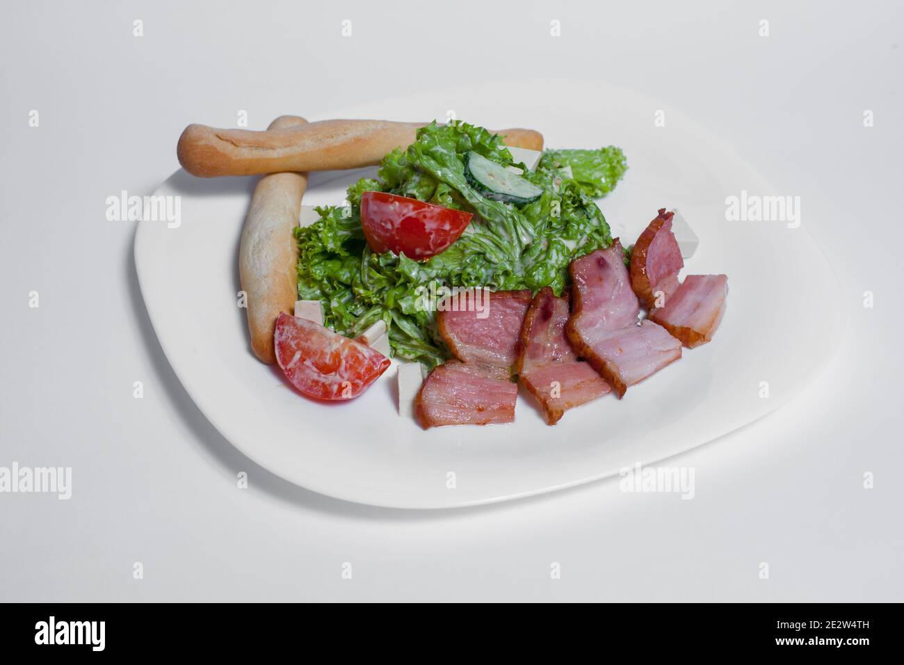 ensalada fresca con tomate, lechuga y tocino a la parrilla sobre fondo blanco Foto de stock
