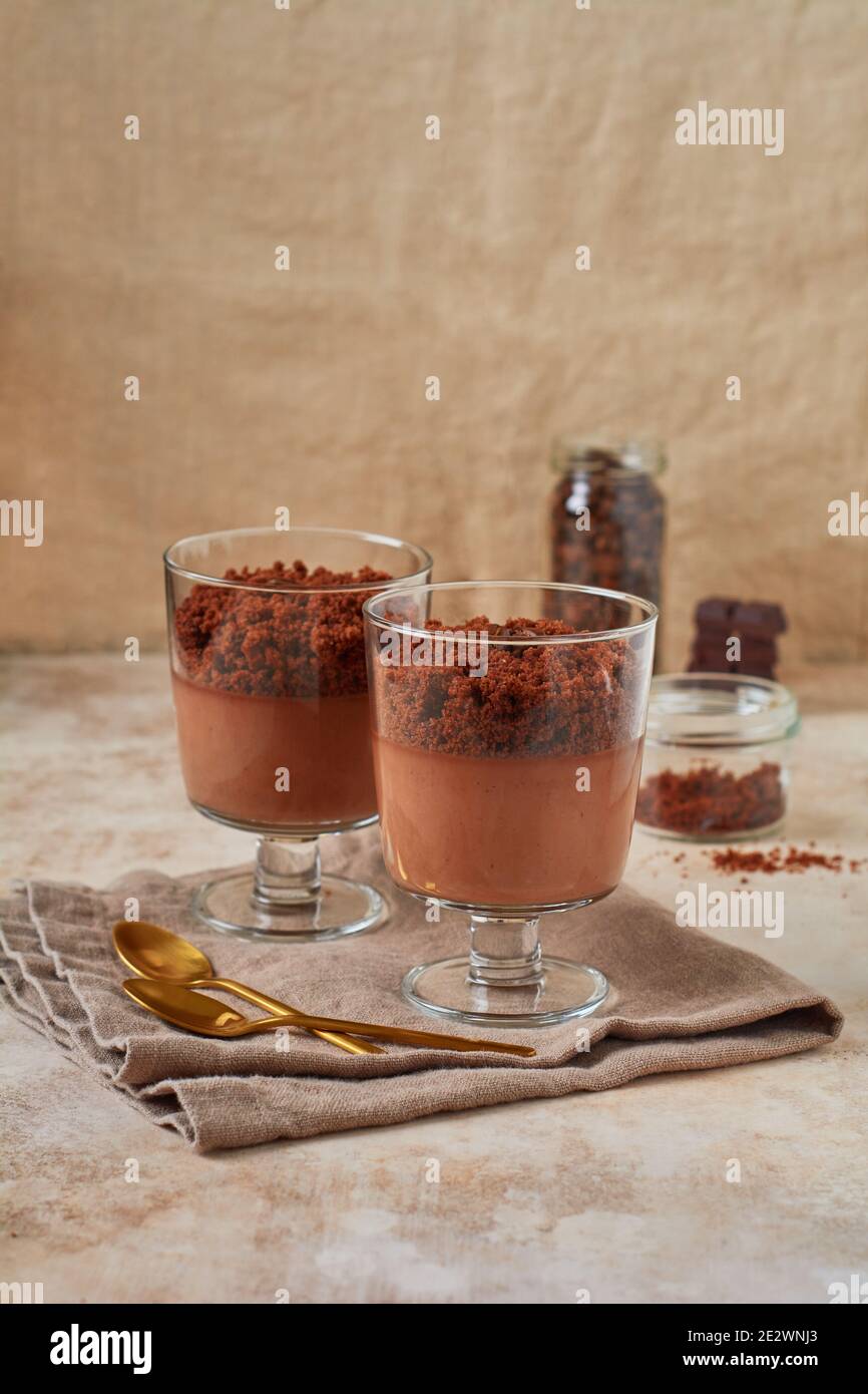 Delicioso postre mousse de chocolate con brownie en tarros de cristal sobre un fondo de pizarra, piedra o hormigón. Foto de stock