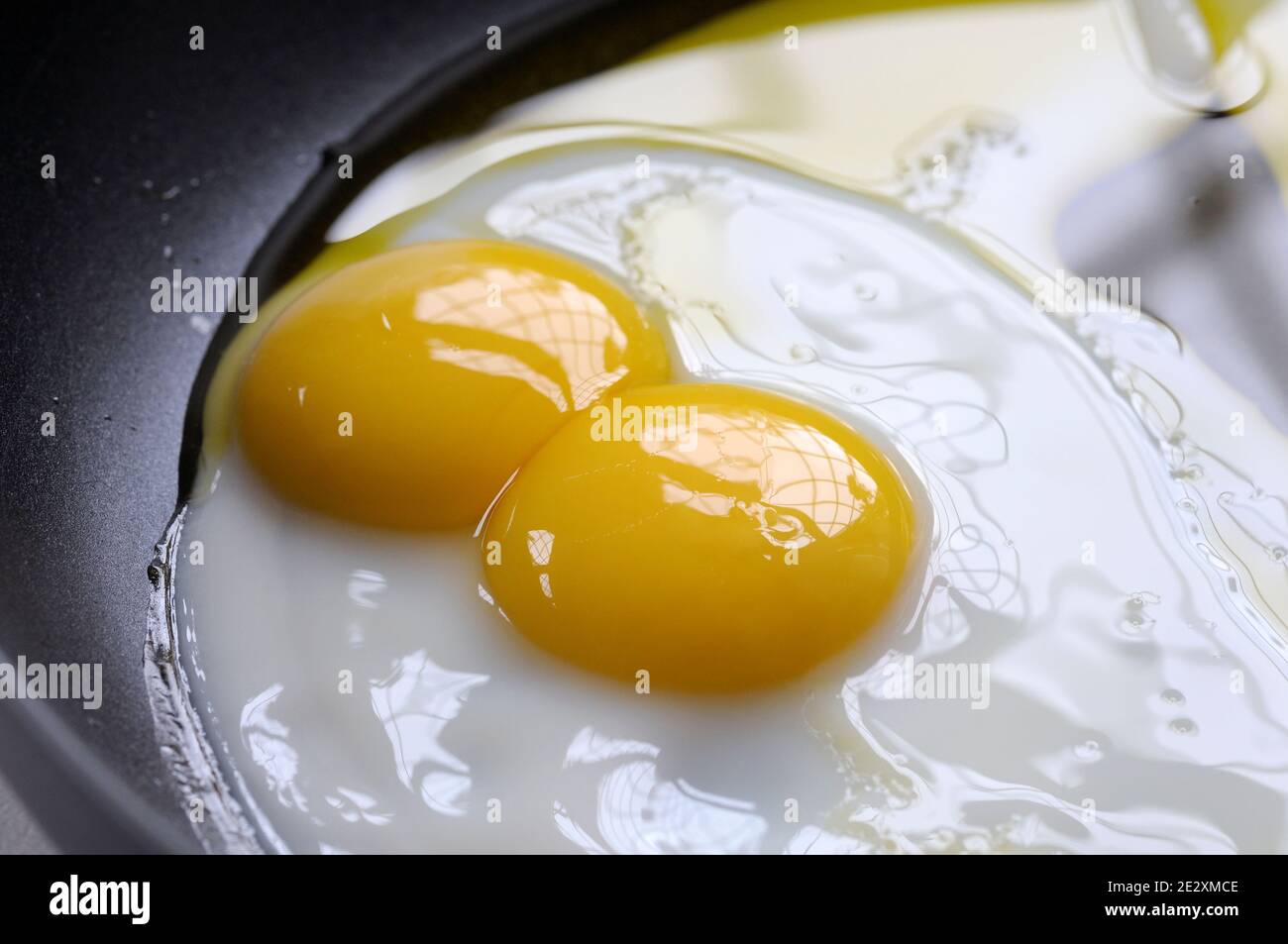 Cocción de huevos fritos de yema doble en aceite en una sartén. Las yemas gemelas son bastante raras y ocurren aproximadamente uno de cada 1,000 huevos. Foto de stock