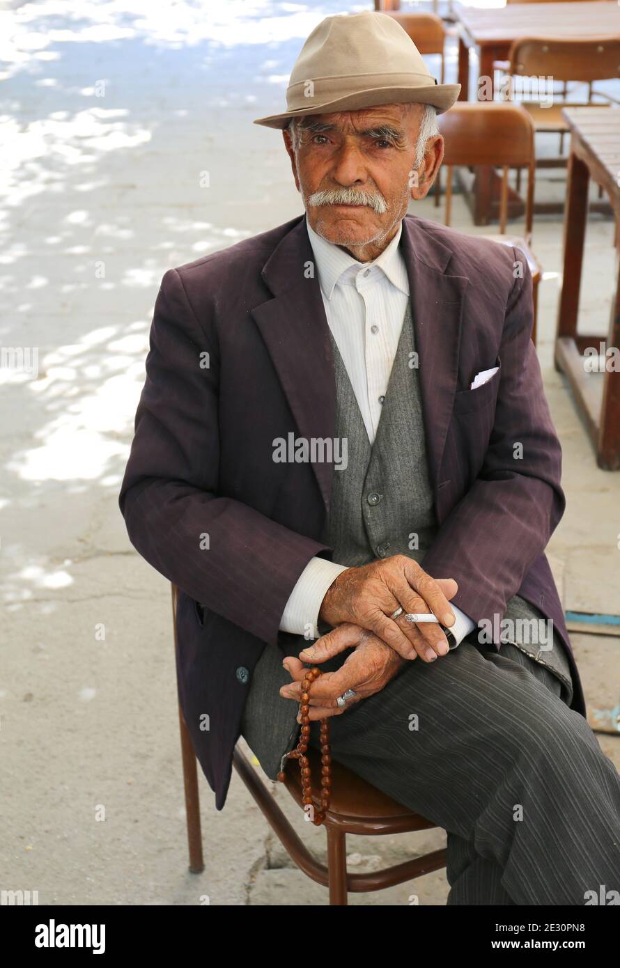 AKSARAY,TURQUÍA-JULIO 22:Viejo caballero turco con cigarrillos, cuentas de oración y sombrero posando en la casa de té local.Julio 22,2017 en Aksaray,Turquía. Foto de stock
