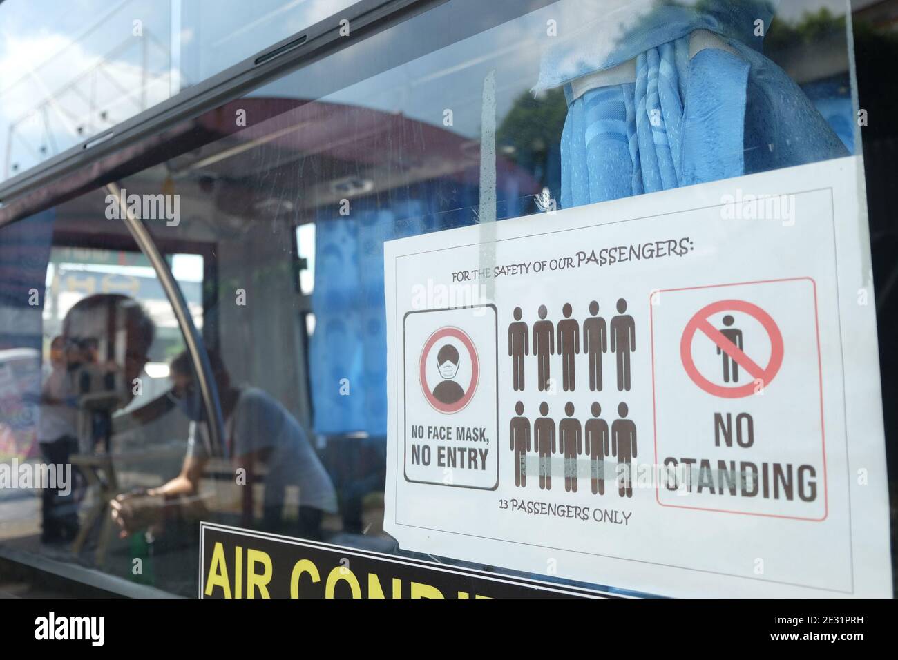 Un letrero colocado fuera del jeepney moderno recuerda a los pasajeros a practicar distanciamiento social mientras que dentro del vehículo, Quezon City. Los jeepneys modernos ahora pueden viajar, pero dentro de rutas seleccionadas. Metro Manila, Filipinas. Foto de stock