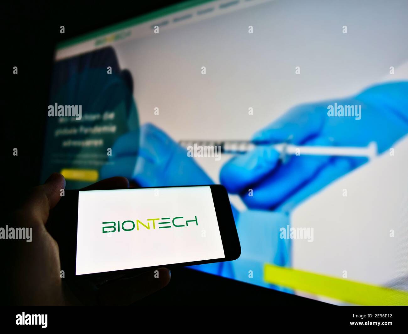 Persona que sostiene el smartphone con el logotipo de la empresa alemana de biotecnología BioNTech, que desarrolló una vacuna Covid-19. Foto de stock