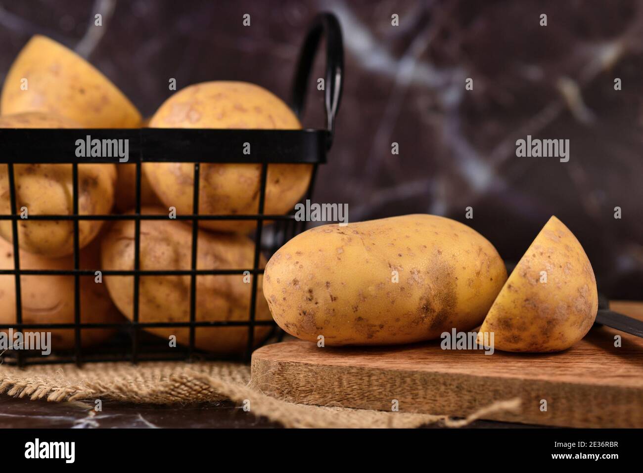 Cortar patatas en tabla de madera con patatas en metal cesta en el fondo  Fotografía de stock - Alamy