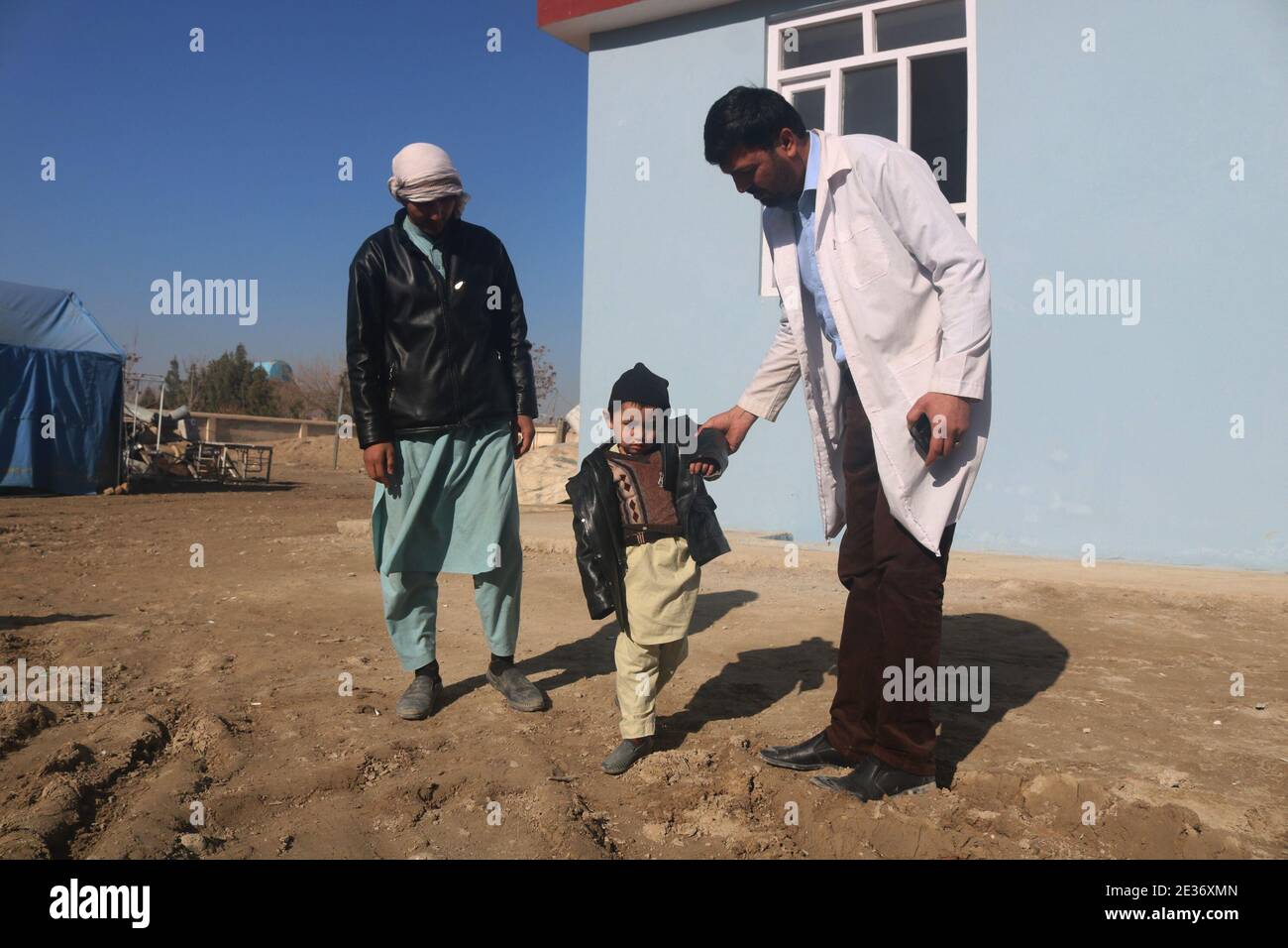 Shiberghan, Afganistán. 17 de enero de 2021. Un trabajador de la salud ayuda a un niño afgano que ha sido infectado por la polio en el distrito de Aqcha en la provincia de Jawzjan, Afganistán, 17 de enero de 2021. El Ministerio de Salud Pública de Afganistán lanzó el domingo una campaña nacional para administrar la dosis de vacunación contra la poliomielitis a 9.9 millones de niños menores de cinco años, informó el Ministerio en un comunicado. Crédito: Mohammad Jan Aria/Xinhua/Alamy Live News Foto de stock