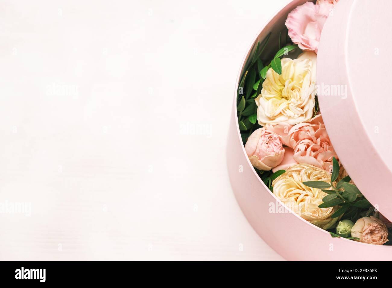 Un arreglo floral elegante y delicado en una caja redonda de sombrero sobre  el fondo rosa con espacio de copia. Caja de regalo para el 8 de marzo, día  Internacional de la