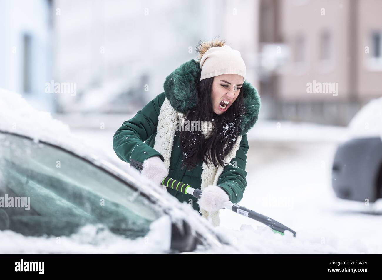 Limpiar la ventana trasera del coche de nieve con un raspador de