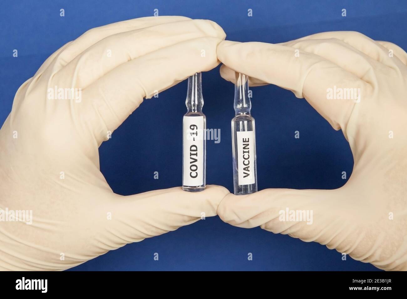 Las manos con guantes médicos sostienen los viales de la vacuna Covid. Primer plano Foto de stock