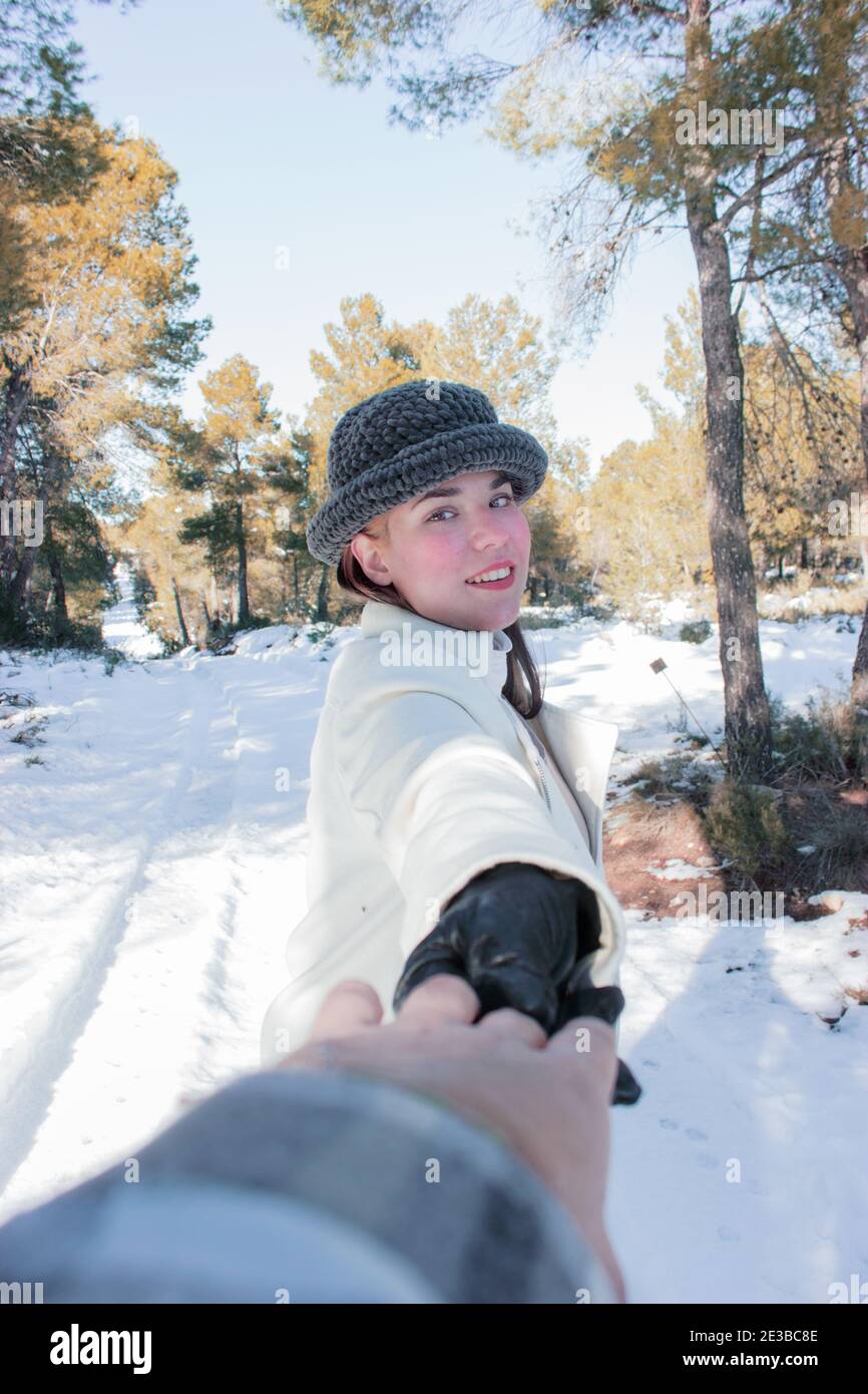Foto de cerca mujer caucásica con sonrisa romántica riendo mientras posaba sobre fondo de nieve con las manos de su novio. Invierno al aire libre 2021. Foto de stock