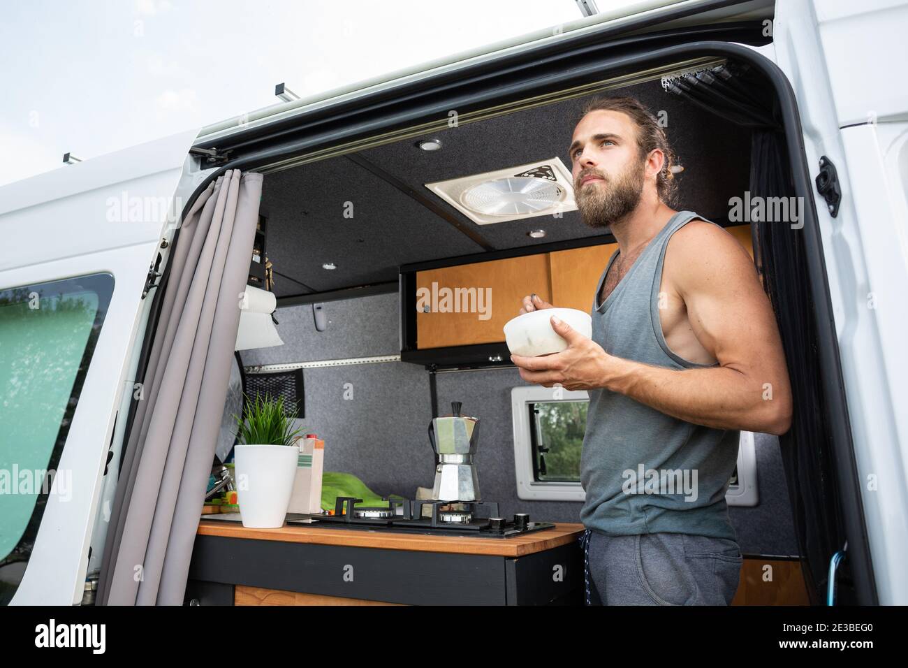 Hombre tomando el desayuno mientras está de pie en su furgoneta campista Foto de stock