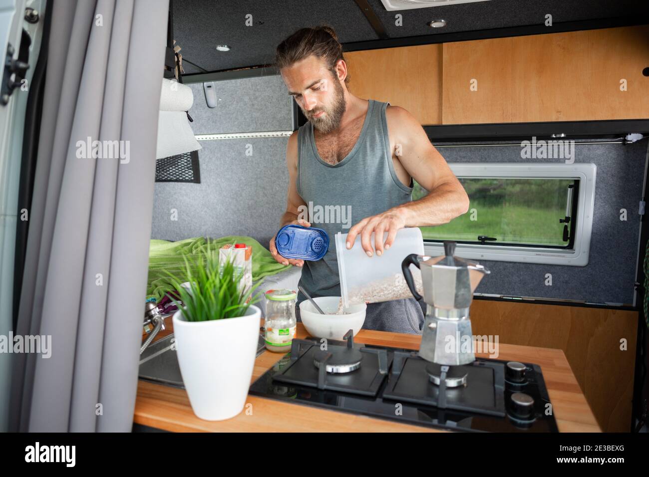 Hombre preparando el desayuno dentro de una furgoneta Foto de stock