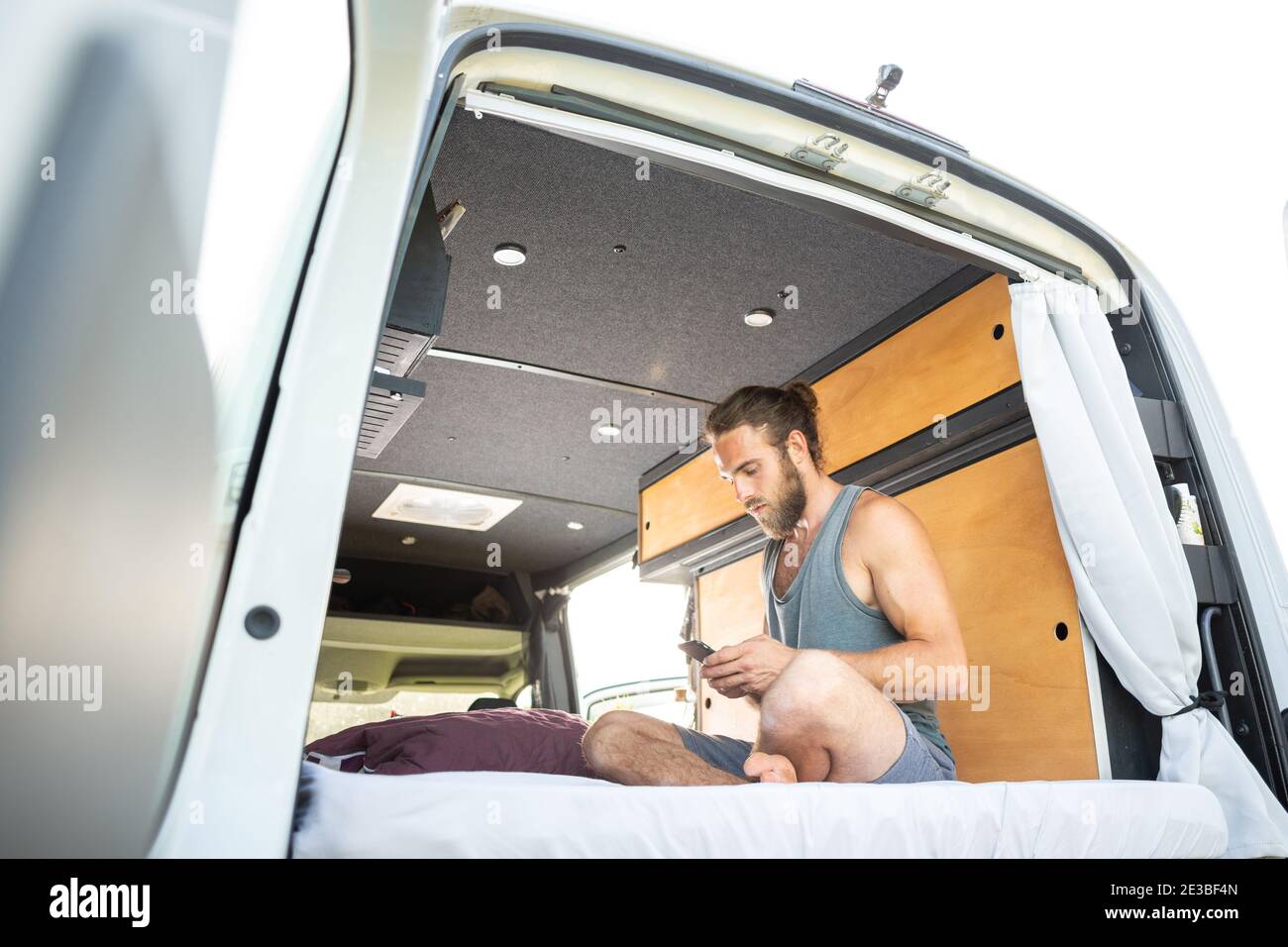 Hombre sentado en su caravana usando un smartphone Foto de stock