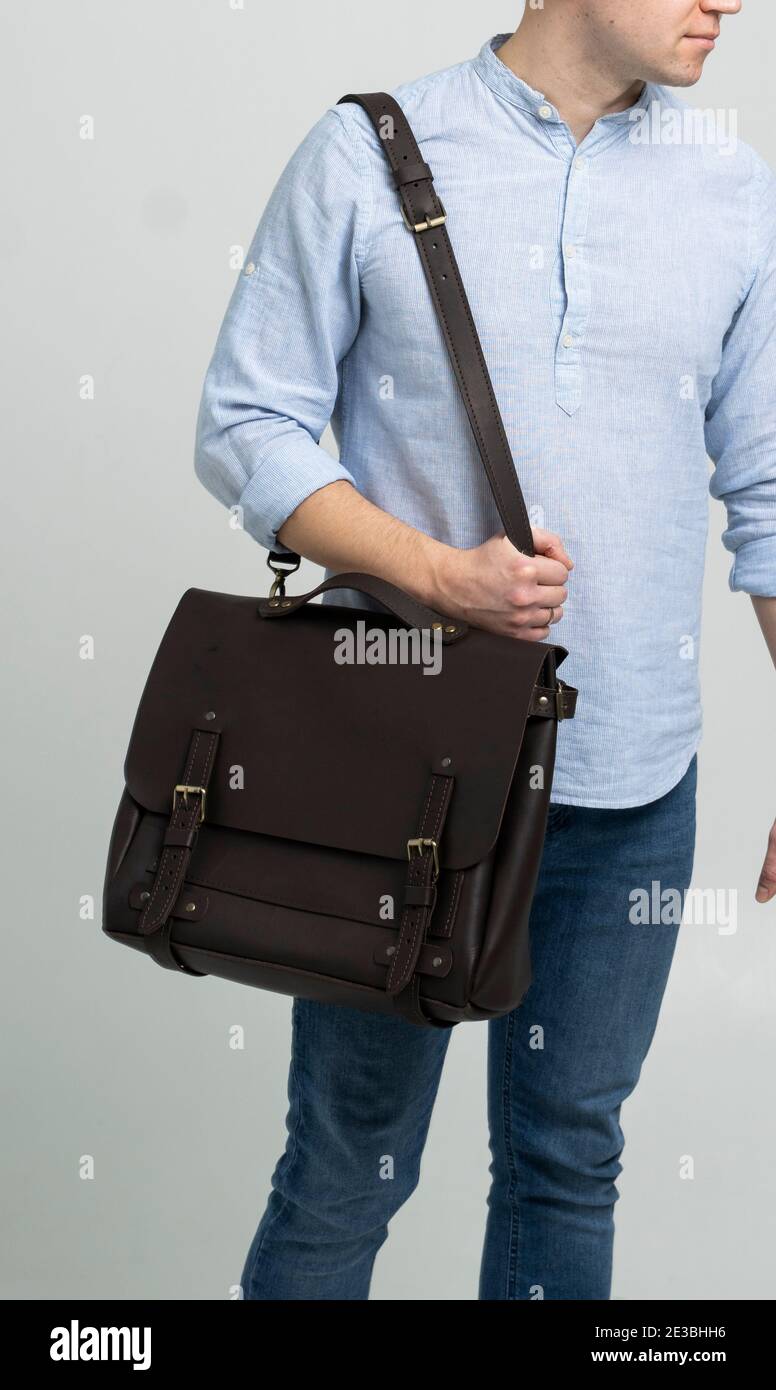 Bolso de cuero marrón para hombre para documentos y portátil en los hombros  de un hombre en una camisa azul y jeans con fondo blanco. Satchel, mens  Fotografía de stock - Alamy