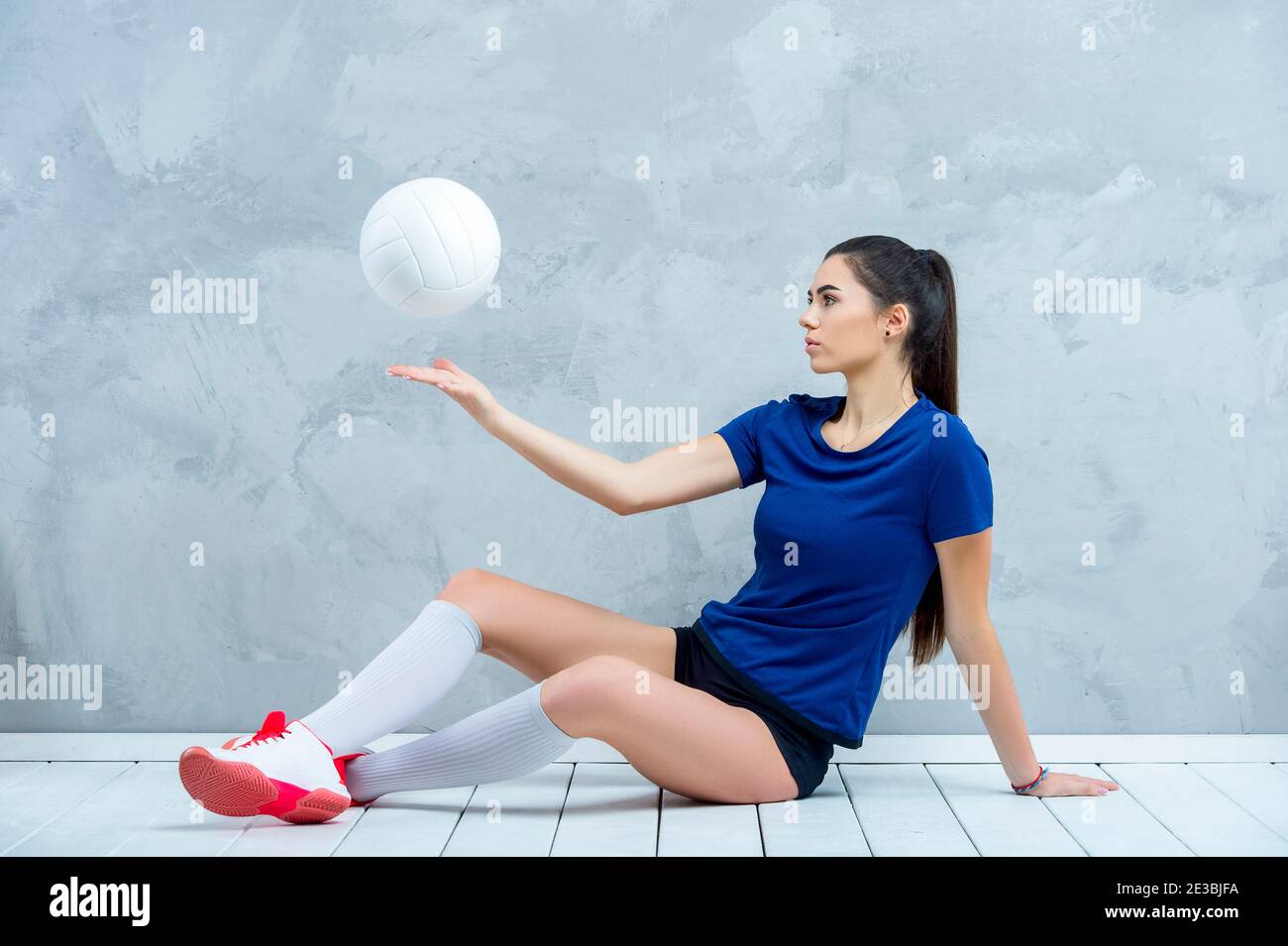 Una chica de voleibol sostiene una pelota blanca en el suelo de madera.  Jugador haciendo entrenamiento deportivo en casa concepto de deporte y  recreación.filtro de color Vintage Fotografía de stock - Alamy