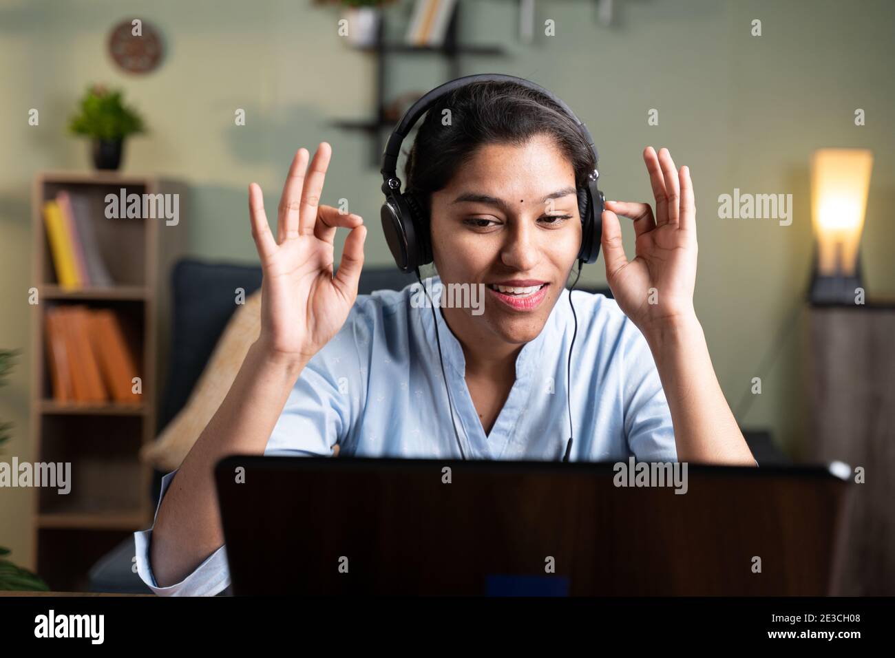 PDV foto de una joven mujer de negocios hablando con la cámara haciendo gesto namaste - concepto de video chat, conferencia o vlogging desde casa mirando a ca Foto de stock